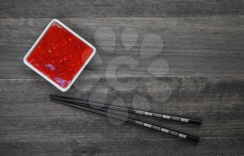 Sweet red sauce and chopsticks on an old wooden background.Top view 