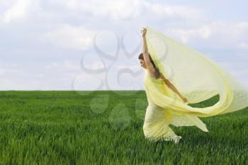 Beautiful girl dancing in a green field