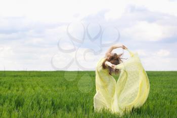 Nice young woman dancing in a green field