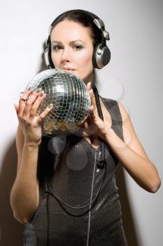 Portrait of nice young brunette in headphones with a mirror ball