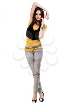 Slim smiling brunette in grey jeans, yellow t-short and black vest. Isolated on white
