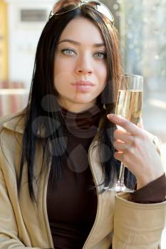 Portrait of nice young brunette with a glass of champagne. Isolated on white