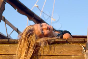 Pretty girl lying on the deck of an old wooden ship