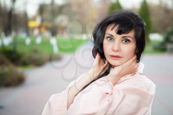 Portrait of pretty young brunette in beige coat posing outdoors