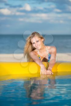 Young sexy blonde posing near yellow pool