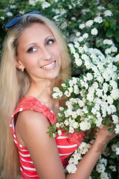 Young blond woman posing near the flowering bush