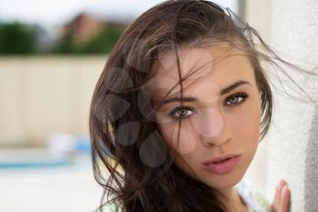 Portrait of flirty young woman posing near the wall