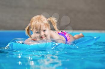 Beautiful little girl swimming on air mattress in water pool