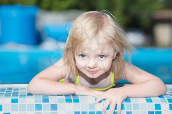 Little blond girl posing in water pool