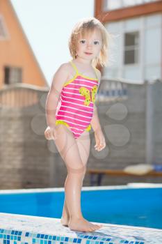 Adorable little girl posing near water pool