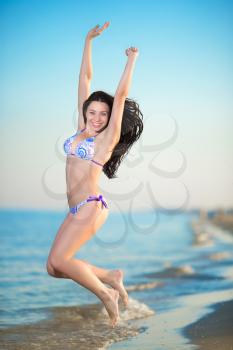 Cheerful young brunette jumping into the sea