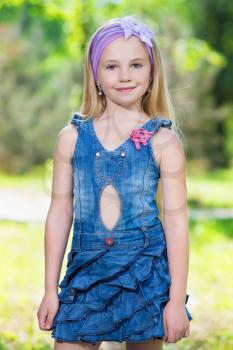Pretty little girl posing in jeans dress outdoors