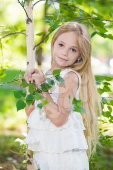 Portrait of nice little girl posing near the birch