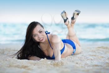 Young woman wearing swimsuit and shoes posing at the seaside