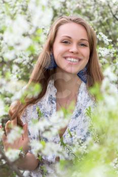 Portrait of young joyful lady posing in blooming garden