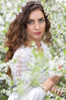 Portrait of young seductive brunette posing in blooming garden