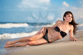 Sexy young woman in black bikini posing on the beach