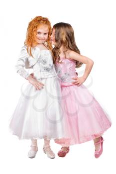 Two little girls in nice dresses whispering. Isolated on white 