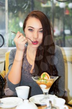 Pretty young brunette having meal in a cozy cafe