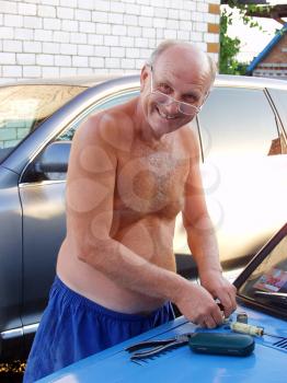 Smiling man with glasses repairing a car