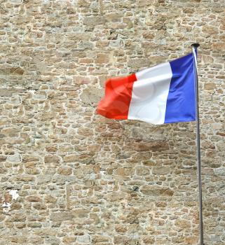 French flag near a stone fortress wall