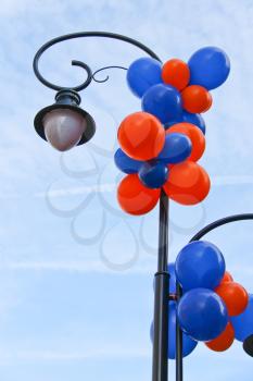 Colourful balloons adorn the column with lantern on a city street