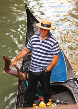 VENICE, ITALY - MAY 06, 2014: Gondolier in a gondola sailing on canal in Venice, Italy