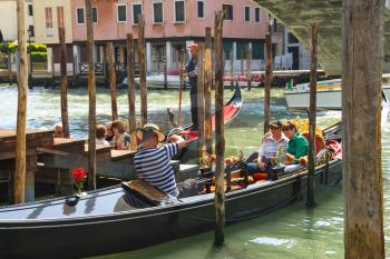 VENICE, ITALY - MAY 06, 2014: Gondolier photographs tourists sitting in a gondola, Venice, Italy