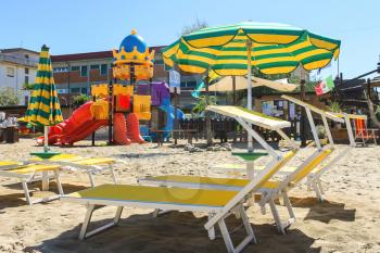 Children's playground, beach chairs and umbrellas on the beach  in the resort town Bellaria Igea Marina, Rimini, Italy