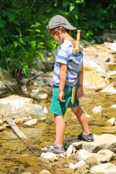 The kid plays near a mountain stream