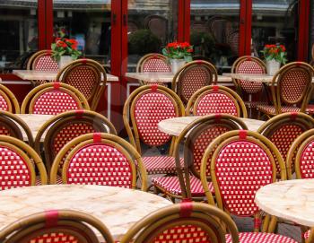 Red and white wicker chairs and small tables in outdoor street cafe