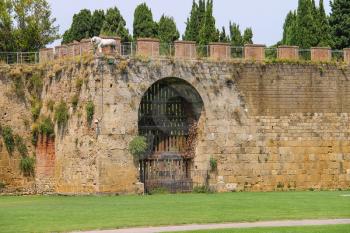 Antique fortified wall and gate with statue of lion. Pisa, Italy