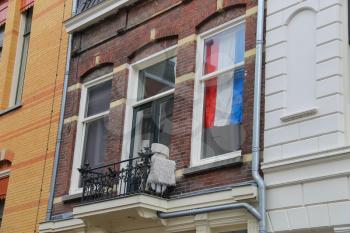 Facade of old building with national flag behind window in Utrecht, the Netherlands
