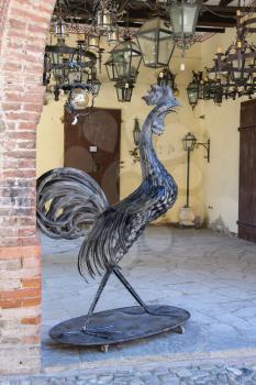 Grazzano Visconti, Italy - August 07, 2016: Metal figure of a rooster and lanterns in vintage style