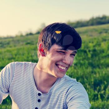 Portrait of a laughing young man outdoors with a butterfly sitting on his head