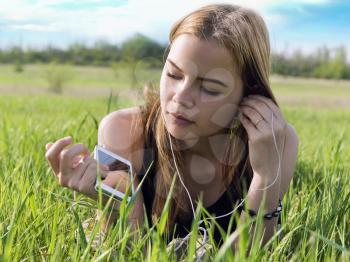 young blond woman listening to music with headphones outdoors