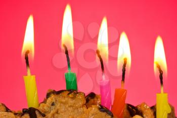 cake with burning candles against red background