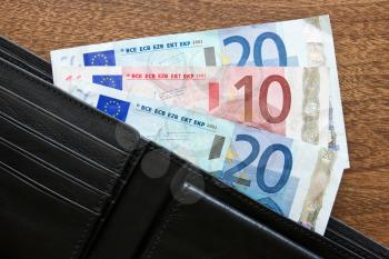 black leather wallet with euros on the table