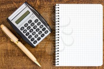 Notebook, pen, and calculator  on wood table background. Business concept 