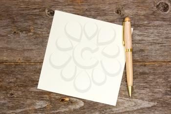 Empty note paper with pen on the wooden background