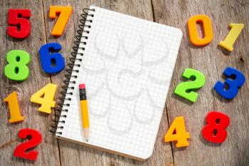 Colorful plastic numbers and empty notebook with pencil