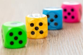 Four colorful dice on the wooden surface. Selective focus.
