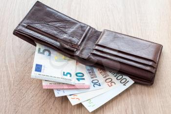 Open wallet with euro banknotes on the wooden table
