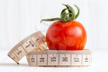 Measuring tape with a small red tomato fruit