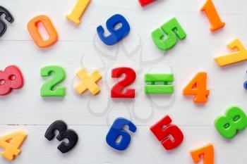 Math example with numbers magnets on a white wood background 
