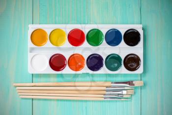 Palette of  multicolor watercolor paints with paint brushes on wooden background
