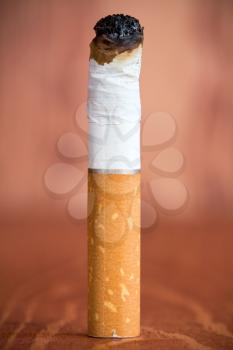 Cigarette butt with a filter  against brown wooden background