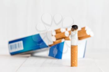Cigarette package and butt on white wooden background