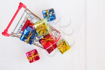 Cart full of colorful gifts on wooden background. Top view.