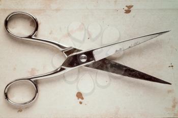 Old scissors on a paper background. Image toned with retro vintage filter